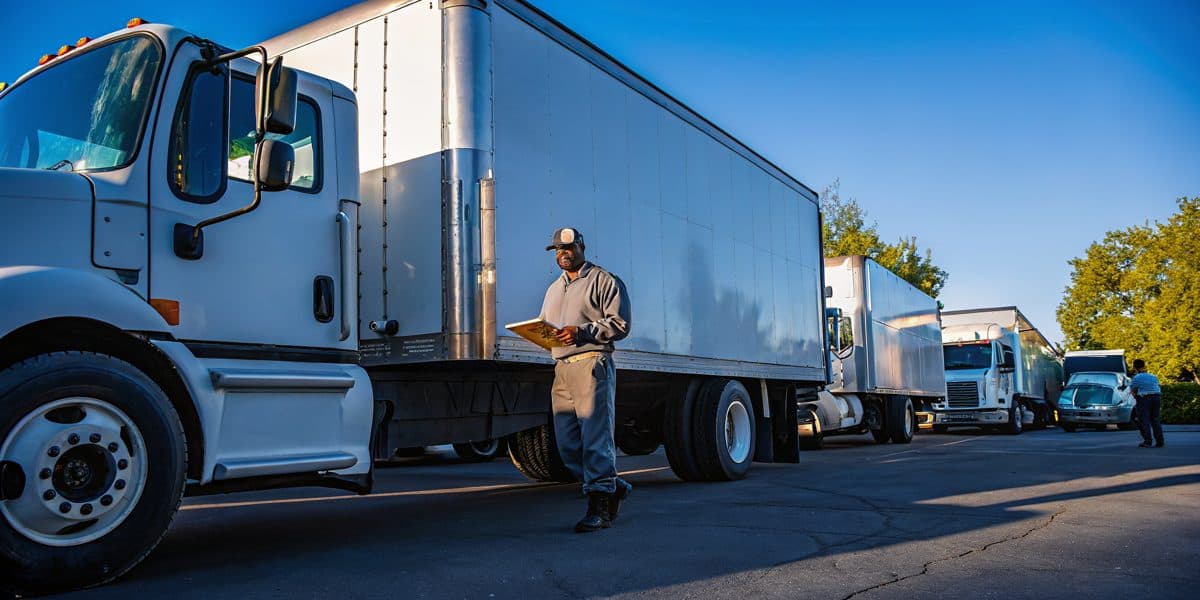 A delivery driver standing beside a white box truck